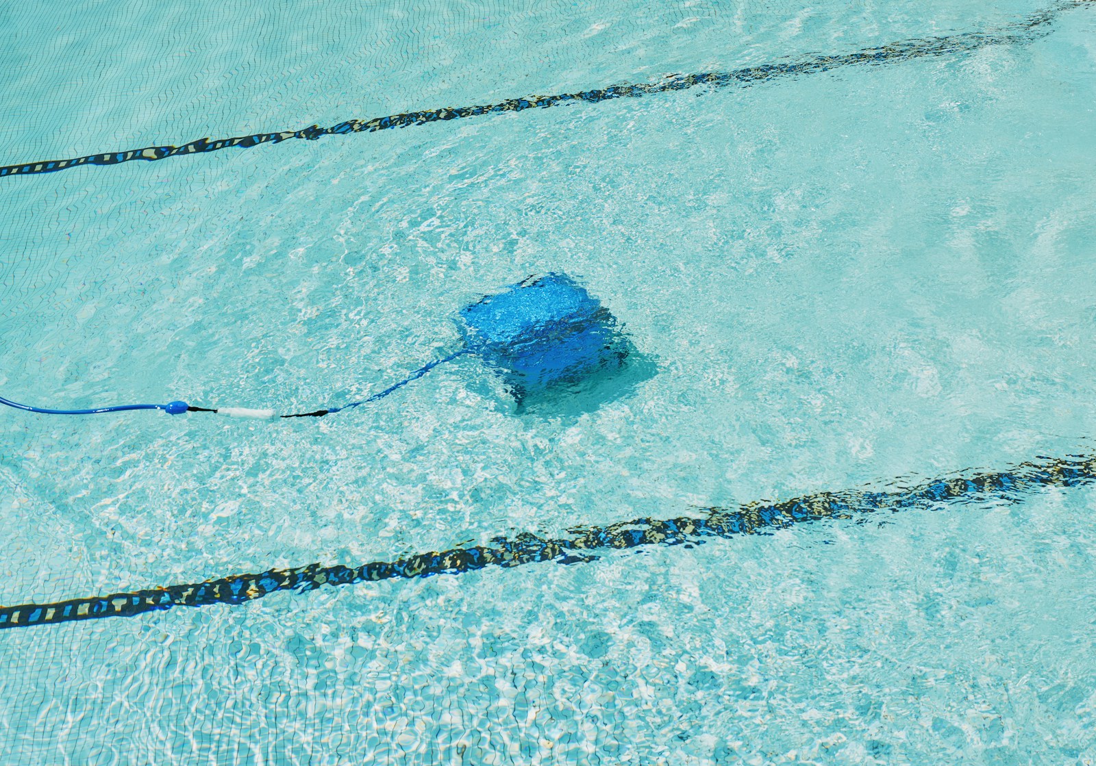 A robotic pool cleaner is working underwater.